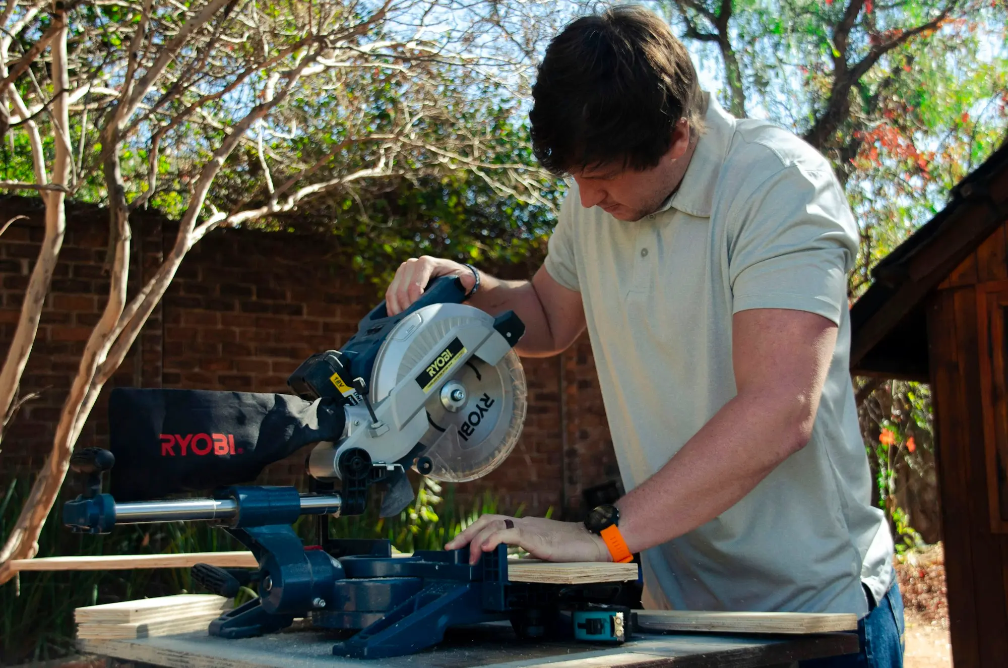 Carpenter cutting timber with a mitre saw at an outdoor workbench