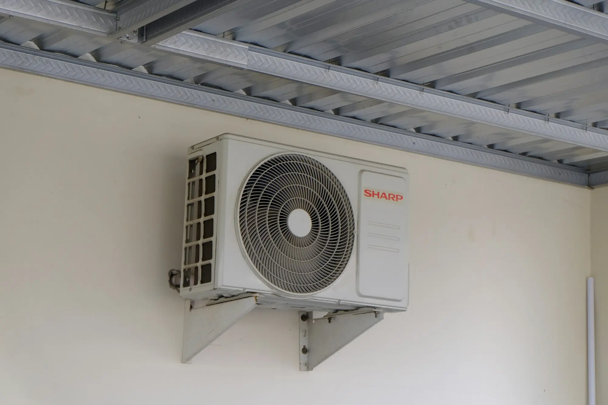 Outdoor air conditioner condenser unit mounted on a wall bracket