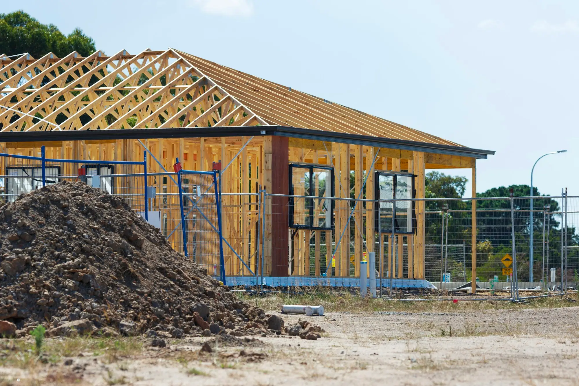 New home site with a pile of excavated soil in front of the timber frame, ready for landscaping